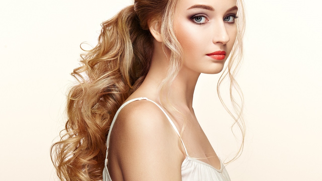 Blonde Girl with Long and shiny Curly Hair. Beautiful Model Woman with Curly Hairstyle. Care and Beauty Hair products. Perfect Make-Up